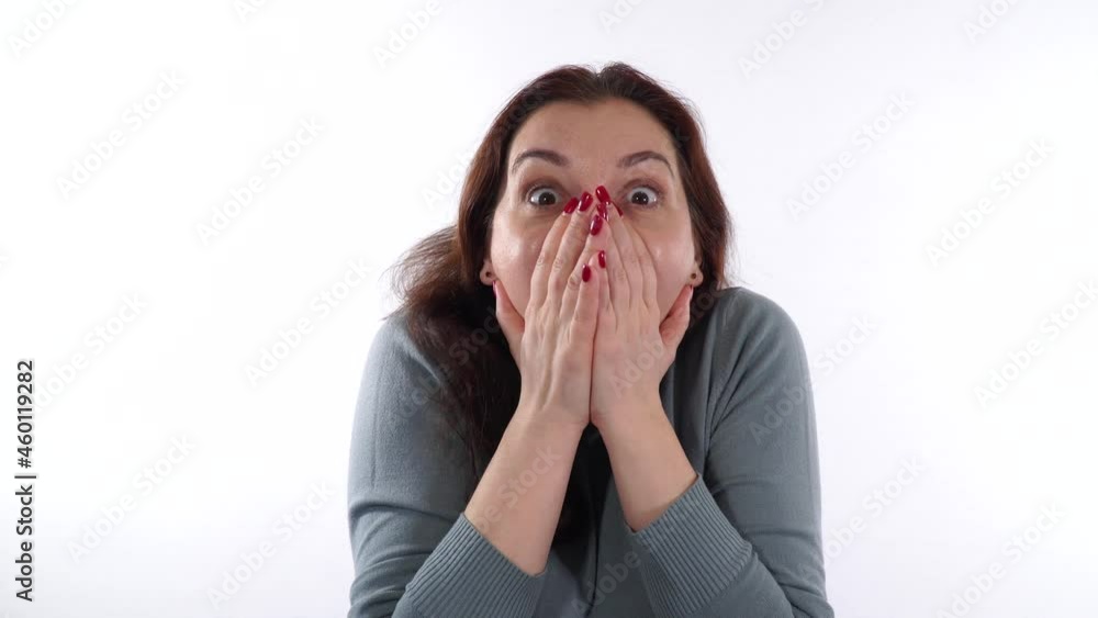 Beautiful woman 30-35 years old brunette shows an emotion of horror or strong surprise. She covers her mouth with her hands. White background. Beautiful woman 30-35 years old brunette shows an emotion of horror or strong surprise. She covers her mouth with her hands. White background.