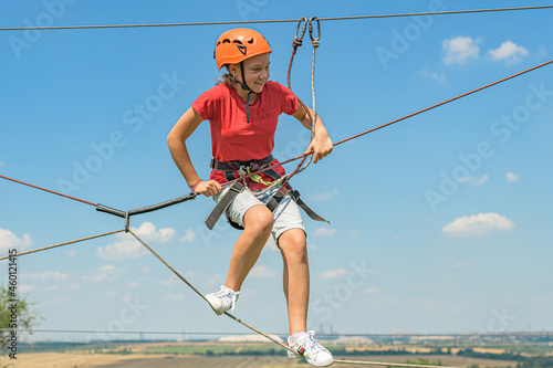 A girl in a sports park on a cable car overcomes obstacles.