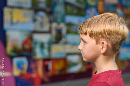 A surprised boy looks at paintings in an exhibition gallery.