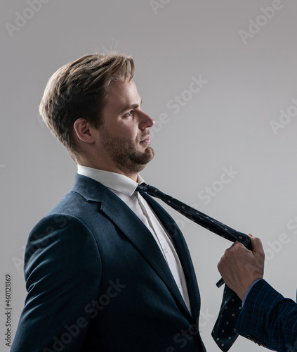 Professional employee man being pulled by necktie during workplace fight grey background, conflict