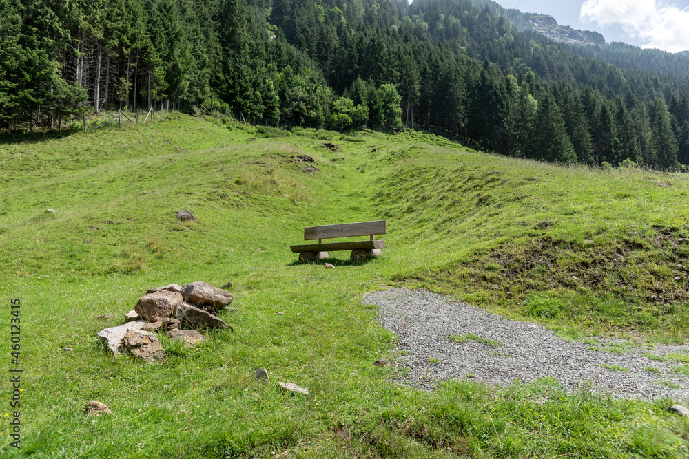 Empty wooden bench to rest on the green meadow in the mountains Empty wooden bench to rest on the green meadow in the mountains