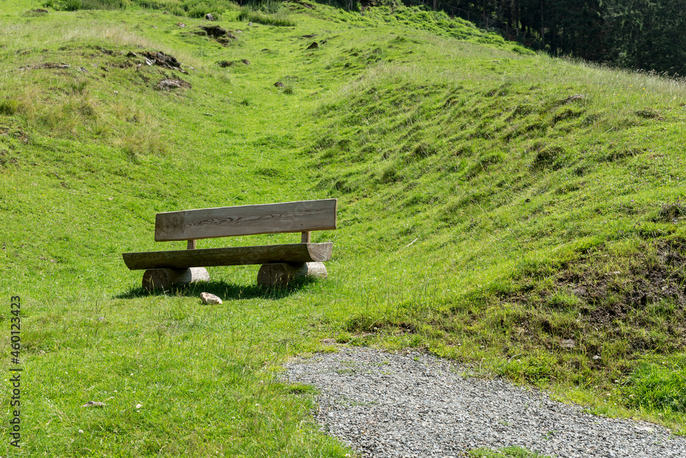 Empty wooden bench to rest on the green meadow in the mountains Empty wooden bench to rest on the green meadow in the mountains