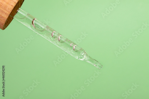 Closeup photography of the pipette with dripping gel.Zero waste wooden cover,mint background.Cosmetics mockup concept.