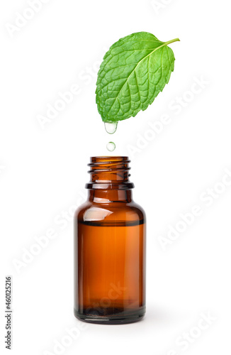 Essential oil mint dripping into amber bottle isolated on white background.