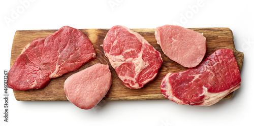 Various types of steak on wooden board isolated on white, from above