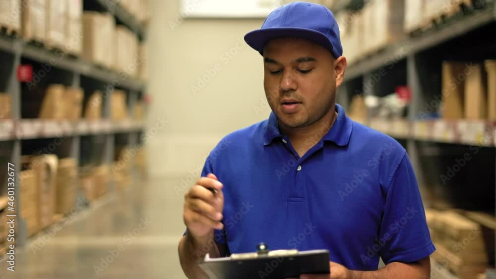Distribution warehouse. Young worker in blue uniform checklist manage parcel box product in warehouse. Asian man employee holding clipboard working at store industry. Supply chain import export Distribution warehouse. Young worker in blue uniform checklist manage parcel box product in warehouse. Asian man employee holding clipboard working at store industry. Supply chain import export