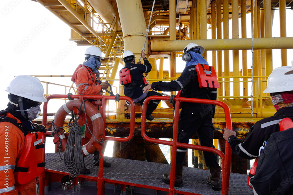 Construction crews are swing rope for transferred by crew boat to oil and  gas platform Stock Photo
