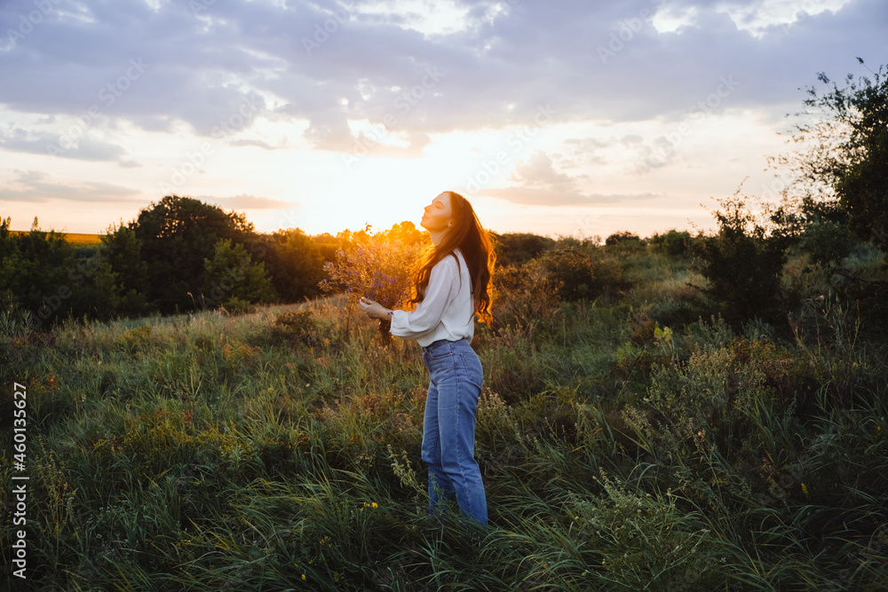 Healing Power of, Benefits Of Ecotherapy, Nature Impact Wellbeing. Happy young woman with long hair and a bouquet of wild flowers enjoy nature and life at sunset