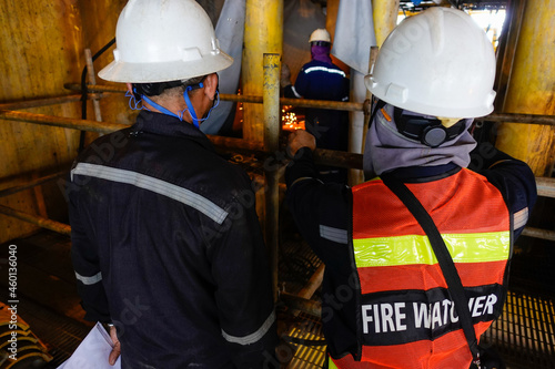 Fire watcher watch welder weld gas pipe casing for stop work in case of gas explosive, working in offshore oil and gas platform rig.