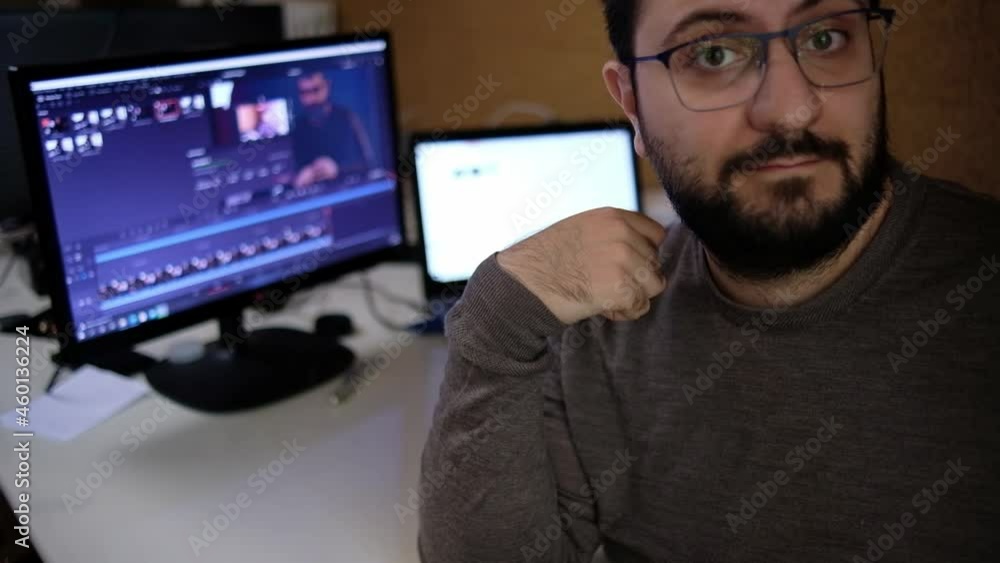a young man, a content creator invites his viewers to subscribe and like his video with his computer in the background a young man, a content creator invites his viewers to subscribe and like his video with his computer in the background
