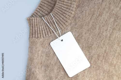 Mock-up of blank white paper price tag or label on sweater background