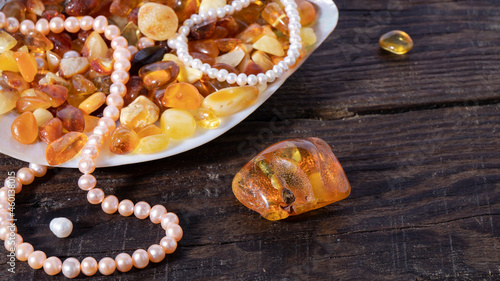 Transparent orange Baltic amber stone and pearl necklace on a wooden surface. Isolated amber jewelry. 