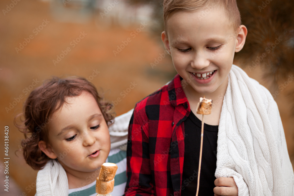 Teen boy and girl kid eating roasted marshmalloy outdoor in a camp. Travel, hike, vacation, camping concept. Teen boy and girl kid eating roasted marshmalloy outdoor in a camp. Travel, hike, vacation, camping concept.
