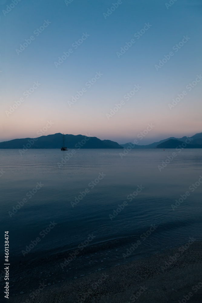 Sea bay before sunrise - calm water surface and faint light