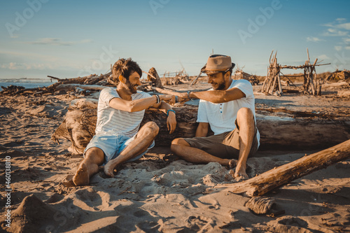 Photography Two boys sitting on the beach greeting each other with their fists