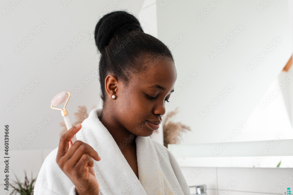 Smiling young woman looking at camera massaging skin by roller Smiling young woman looking at camera massaging skin by roller