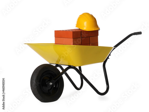 Obraz na plátně Red bricks and hard hat in wheelbarrow on white background