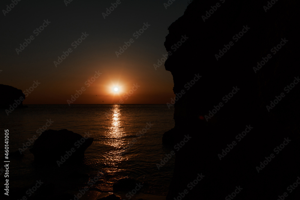 waves wash the rocky shore of the sea. Sunset. Reflection in the water of the bridge and rays