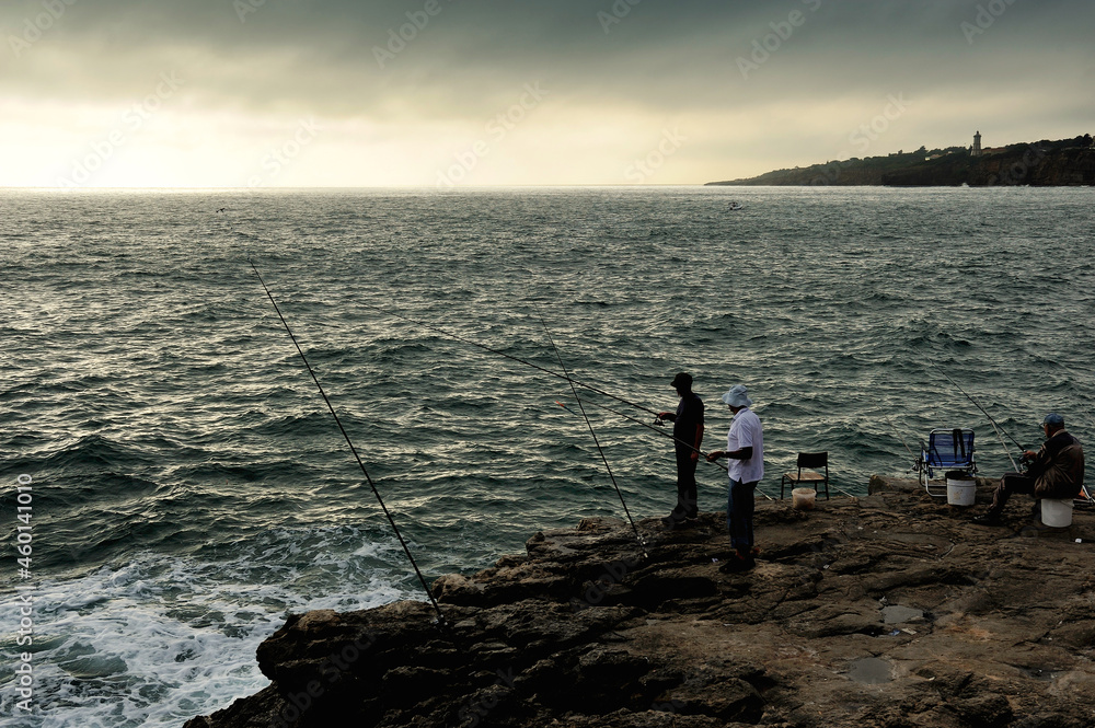 three fishermen on the coast in twilight