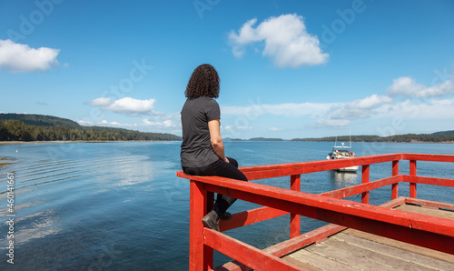 White Caucasian Woman on a Wooden Pier by the Pacific Ocean West Coast. Sunny Summer Day. Fernwood Point Beach, Salt Spring Island, British Columbia, Canada.