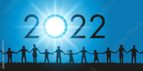 Un groupe d’hommes et de femmes de tous les âges ainsi que des enfants se donnent la main en signe de fraternité pour l’arrivée de l’année 2022.