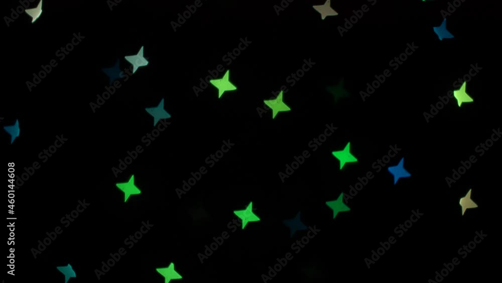 Flashing bokeh lights stars on decorative garland on black background. Festive blinking green, blue, red and yellow. Concept: Christmas, New Year, Holiday. Flashing bokeh lights stars on decorative garland on black background. Festive blinking green, blue, red and yellow. Concept: Christmas, New Year, Holiday.