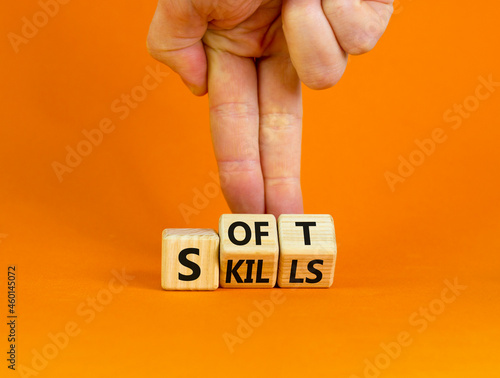 Soft skills symbol. Businessman turns wooden cubes and changes the word 'soft' to 'skills' or vice versa. Beautiful orange background, copy space. Business, soft skills concept.