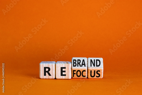 Refocus and rebrand symbol. Turned cubes and changed the word 'refocus' to 'rebrand'. Beautiful orange table, orange background. Business, refocus and rebrand concept. Copy space.
