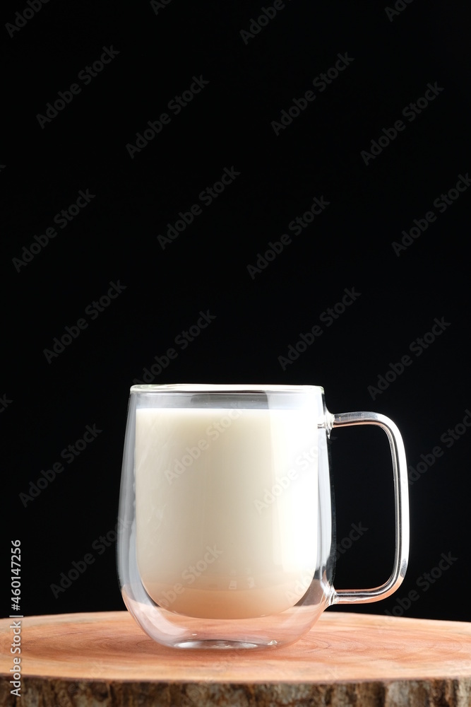 a glass of milk on a wooden coaster on a black background a glass of milk on a wooden coaster on a black background