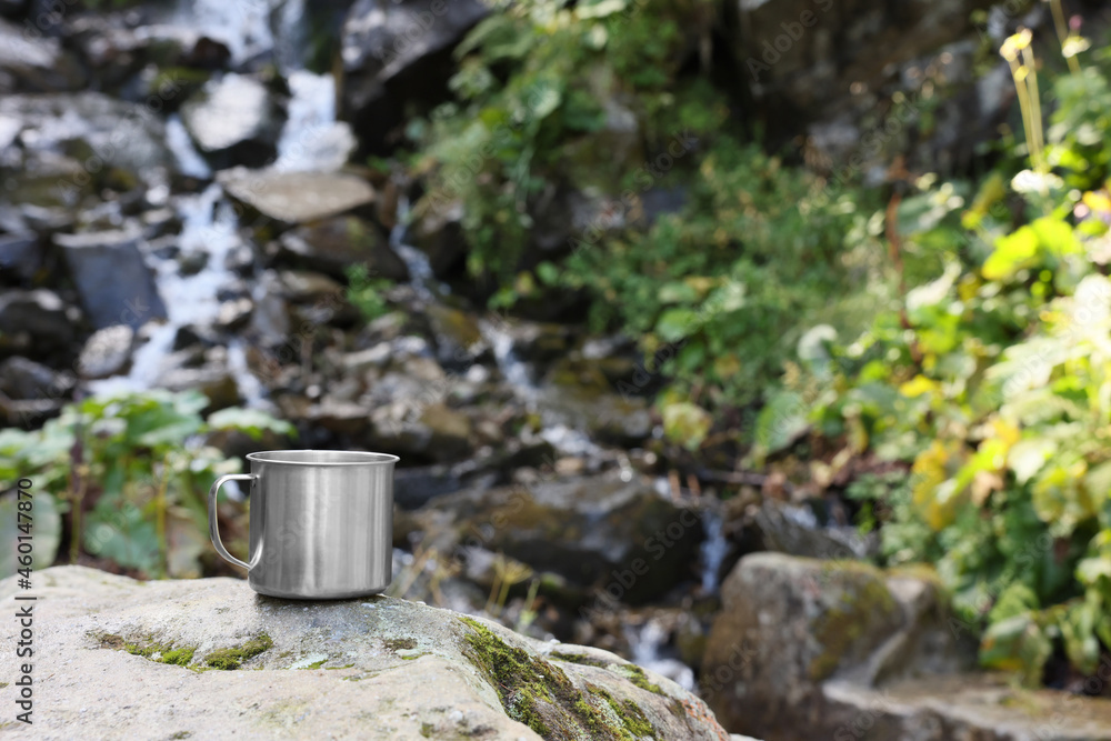 Cup on rock near mountain waterfall. Space for text Cup on rock near mountain waterfall. Space for text