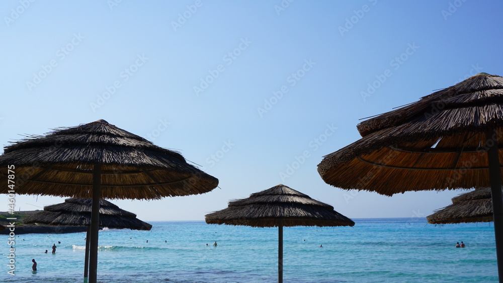 straw umbrellas from the sun on the background of blue sky and sea summer beach vacation