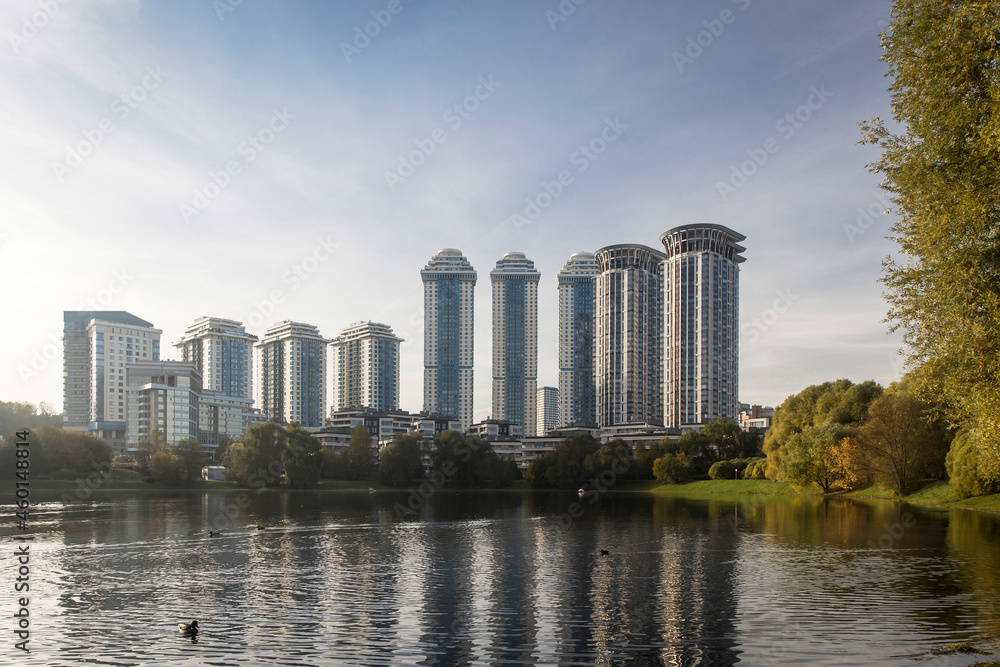 Round multi-storey buildings are reflected in a small pond near the Minskaya metro station