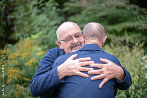 A married, elderly gay male couple embrace each other in a show of love and affection. photo