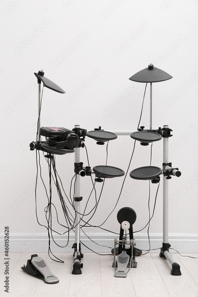 Modern electronic drum kit near white wall indoors. Musical instrument Modern electronic drum kit near white wall indoors. Musical instrument