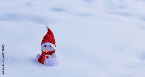 Christmas banner with snow and a snowman in a red scarf and a hat, a toy snowman in a snowdrift in winter © Leka
