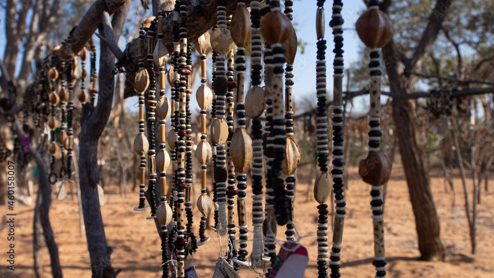 Close up of strings of African necklaces made from beads and seeds on display at an outdoor market in Namibia. Background blurred or out of focus