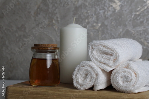 oil for body massage white candle towels snail on a wooden tray on a gray background side view. Spa relaxation massage. Body care
