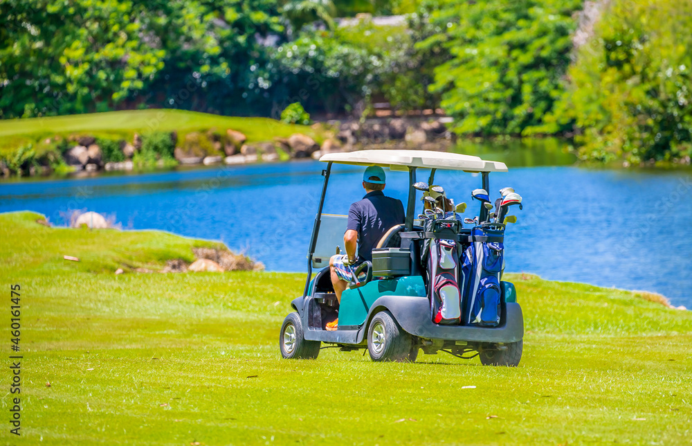 Golfers drive a golf car across a golf course in the Seychelles. Golf sport in the background of a tropical landscape.