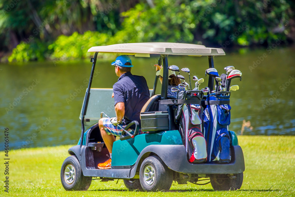 Golfers drive a golf car across a golf course in the Seychelles. Golf sport in the background of a tropical landscape. Golfers drive a golf car across a golf course in the Seychelles. Golf sport in the background of a tropical landscape.