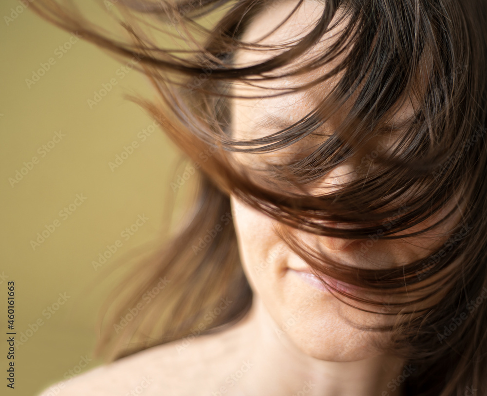 Wellness, cosmetics and hairstyle. Portrait of beautiful woman model with flying straight hair whicking across her face. Focus on the hair Wellness, cosmetics and hairstyle. Portrait of beautiful woman model with flying straight hair whicking across her face. Focus on the hair
