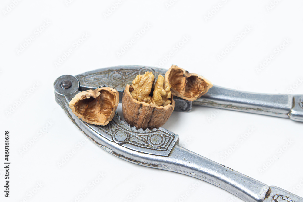 Walnuts on a white background. Chopped walnut next to a nutcracker. Walnuts on a white background. Chopped walnut next to a nutcracker.