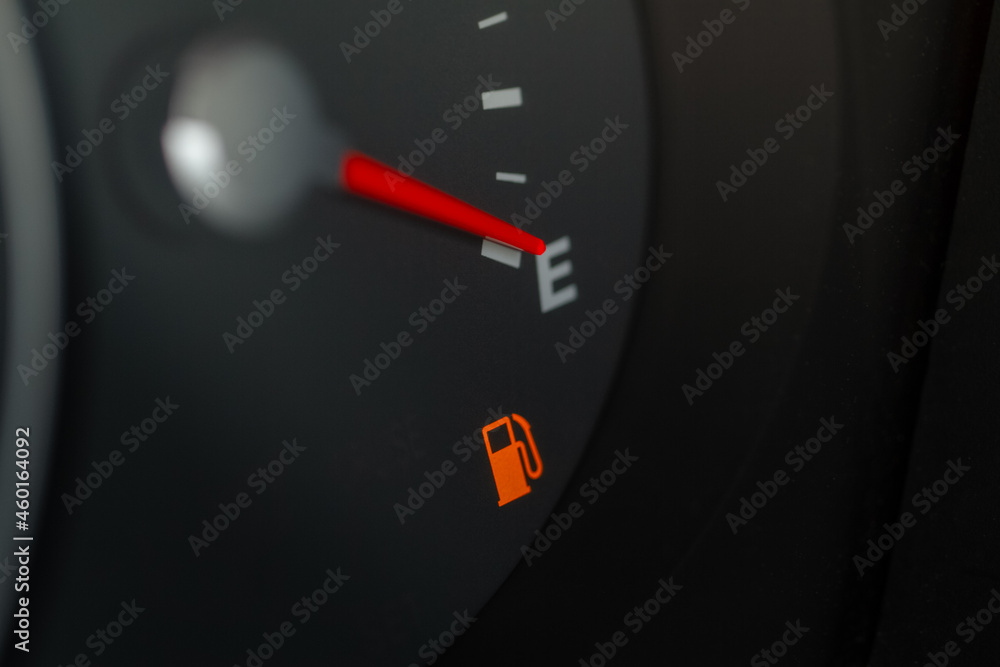 Naklejka premium Modern car fuel gauge showing empty tank. Close up view of empty fuel warning light.