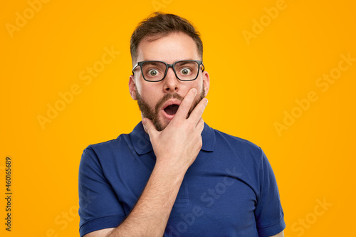 Shocked man with hands on yellow background