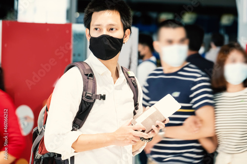 asian Man holding passport wearing a mask for prevent virus in international airport waiting for flight aircraft. Protection against Coronavirus