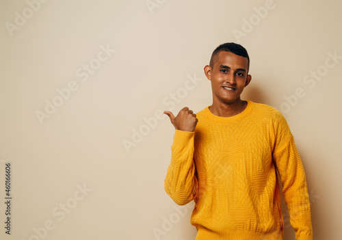 Young latinx man pointing finger to the side over isolated brown background. photo
