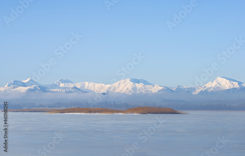 snowbound mountain chain beyond frozen lake at bright winter day © Yuriy Kulik