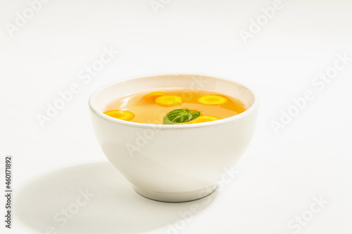 Transparent chicken broth with vegetables in ceramic bowls