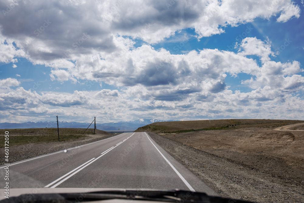 Asphalt road to the horizon through the windshield of a car. Travel in the Altai Republic in summer. Asphalt road to the horizon through the windshield of a car. Travel in the Altai Republic in summer.