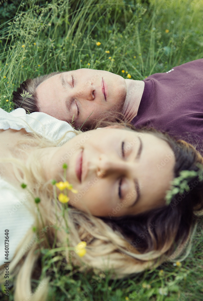 Austria, Vienna, Young couple with eyes closed lying on grass Austria, Vienna, Young couple with eyes closed lying on grass