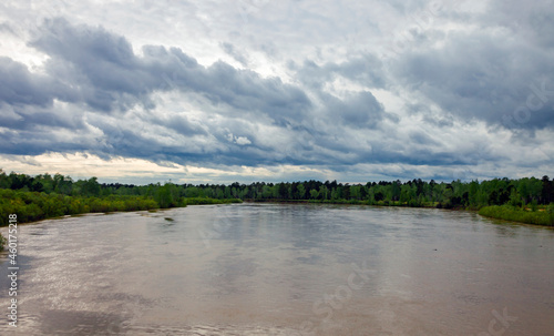 High water level on the Siberian river in early summer and a cloudy landscape.